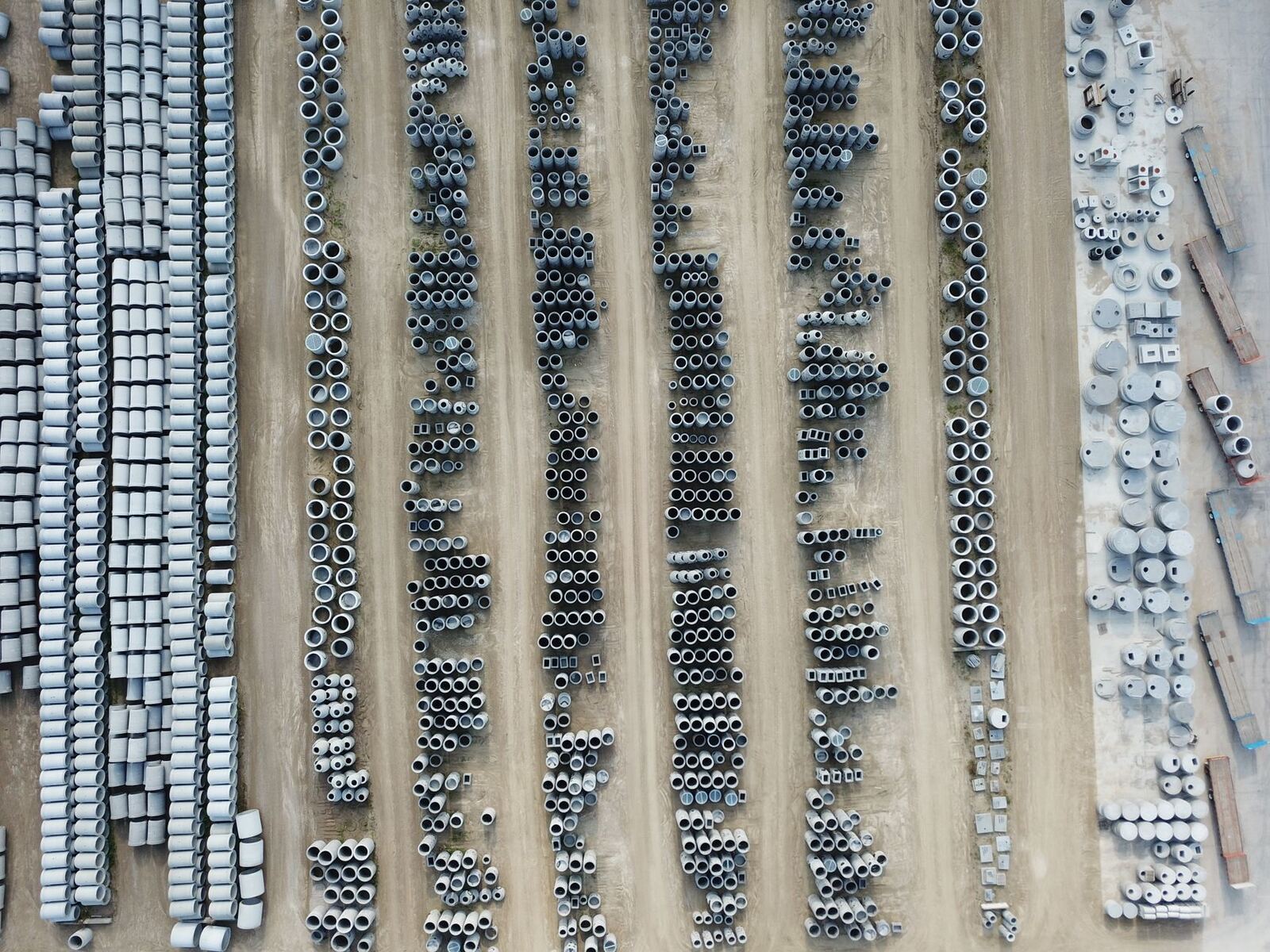 Drone shot of an organized outdoor concrete manufacturing facility with various pipes.