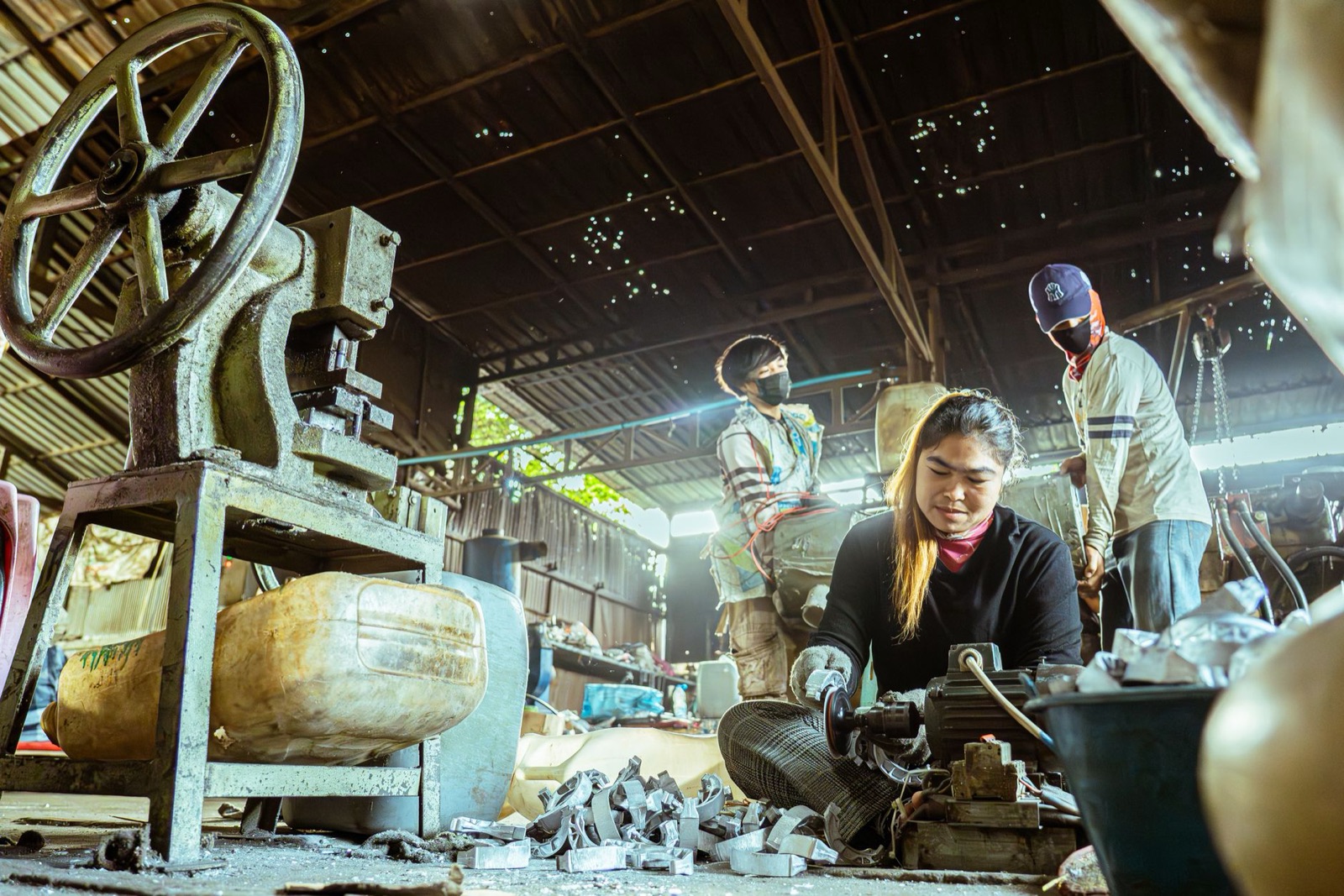 Industrial workers operating machinery in a factory setting, showcasing teamwork and manual labor.