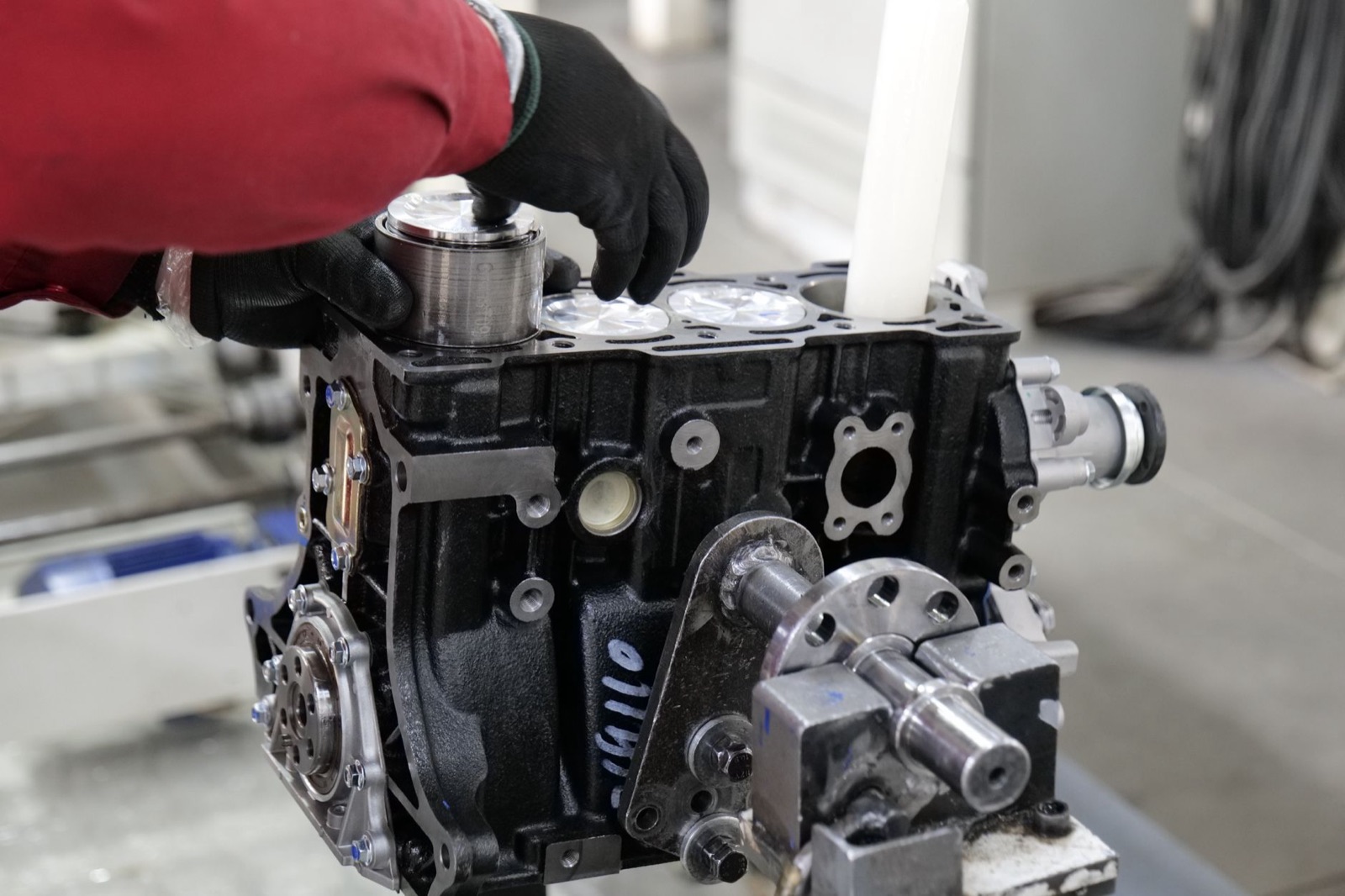 Mechanic working on engine assembly in a workshop, focusing on precision and craftsmanship.