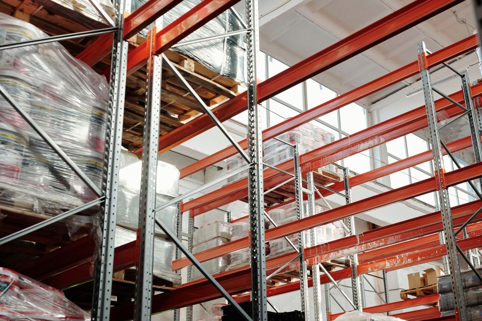 Bright modern warehouse featuring pallets and storage racks for logistics and inventory management.